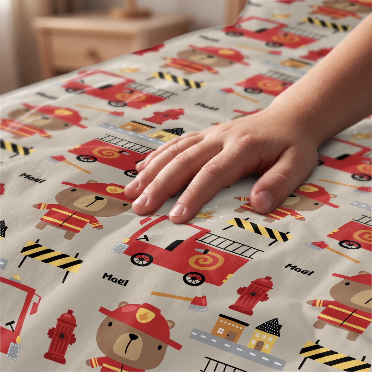Main caresse le tissu de la parure de lit Pompier avec ours pompiers et prénom market_france