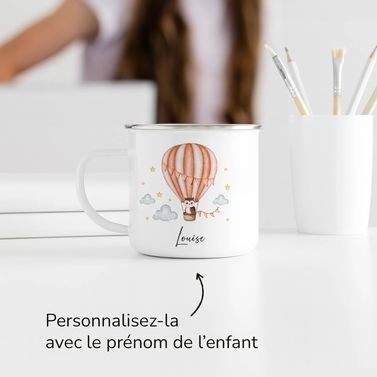 Tasse Montgolfière orange avec prénom sur un bureau près de pinceaux market_france