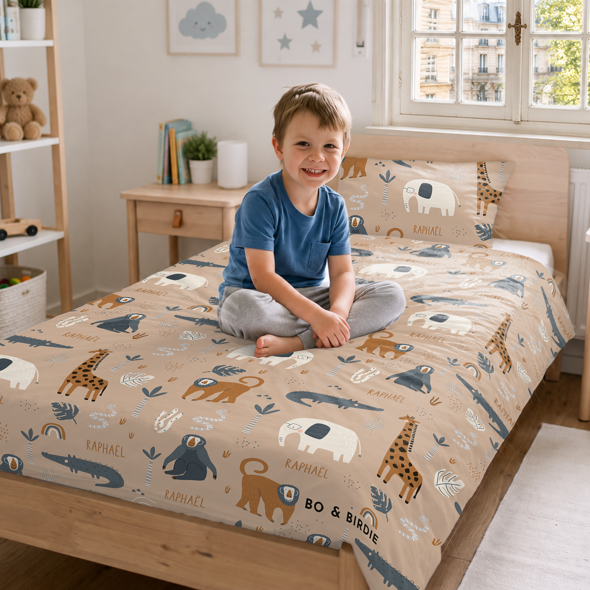 Garçon souriant assis sur le lit avec la parure Savane et le prénom market_france