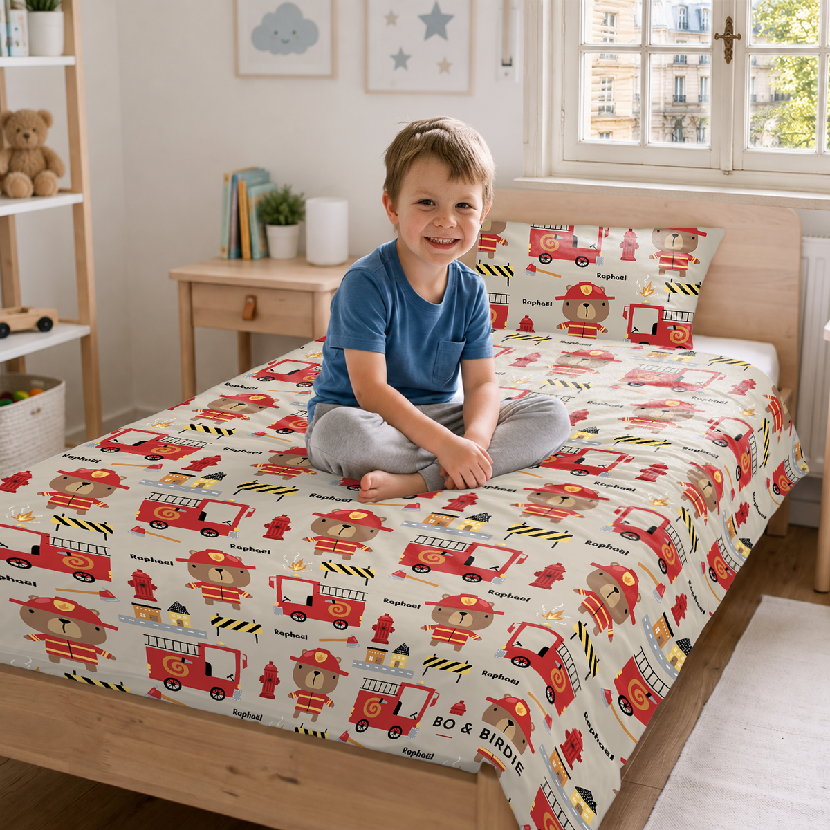 Petit garçon souriant assis sur un lit avec la parure Pompier market_france