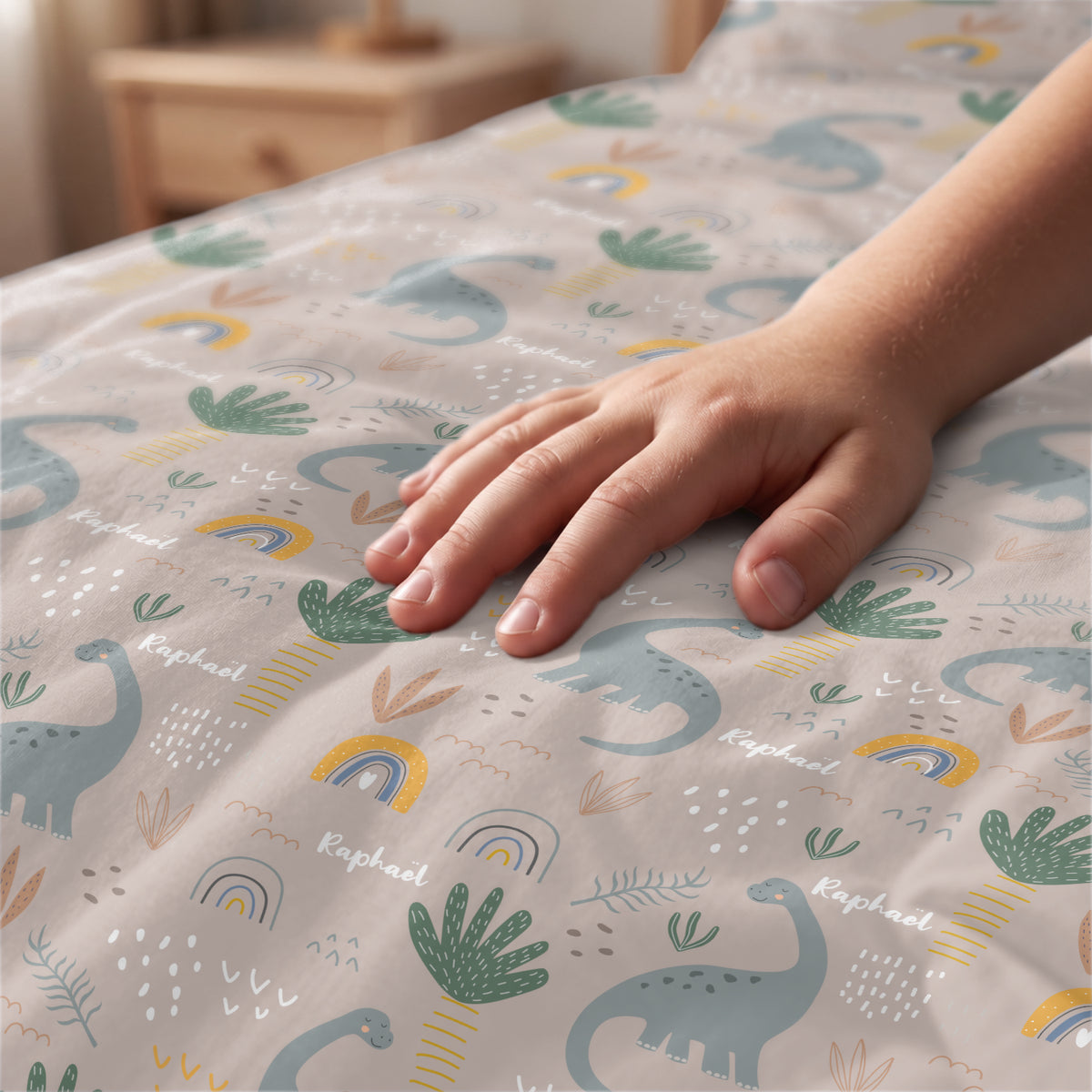 Main caresse le tissu de la parure de lit Dinosaures avec arcs-en-ciel market_france