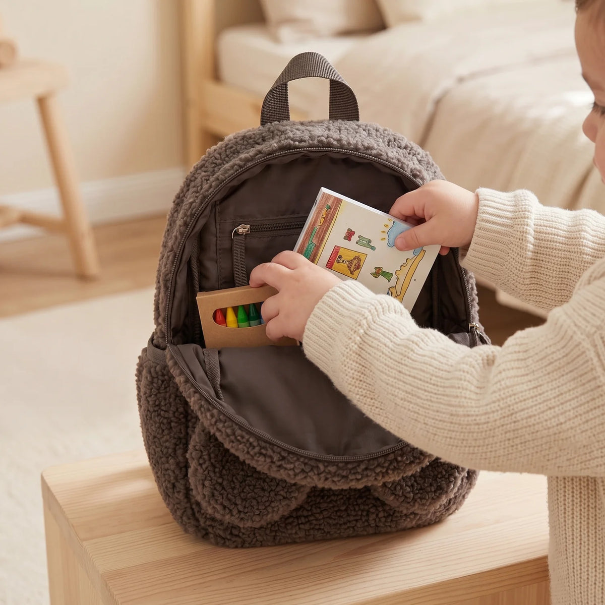 Enfant rangeant un livre dans le sac à dos ourson taupe ouvert | market_france