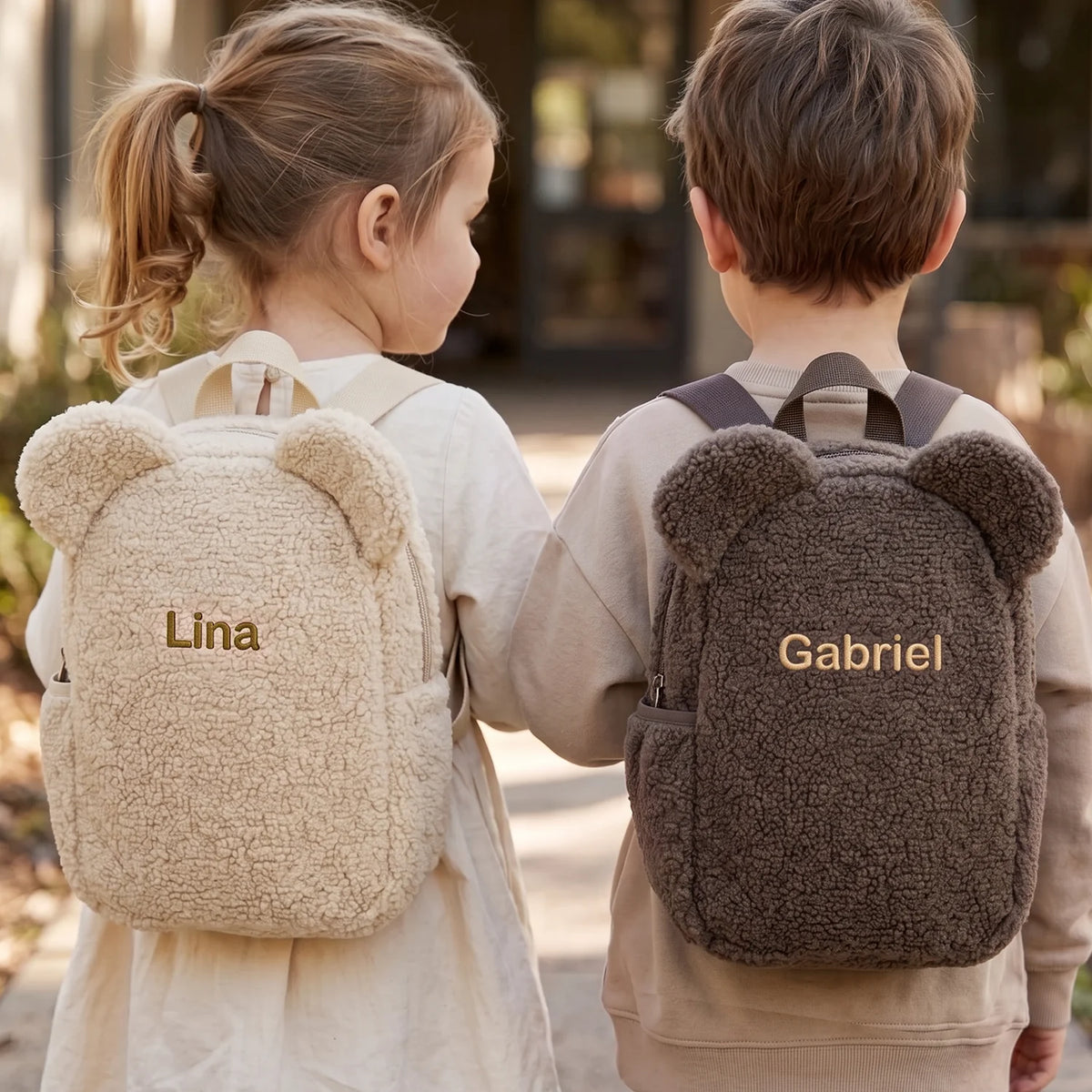 Deux enfants avec des sacs à dos ourson beige et taupe brodés des prénoms « Lina » et « Gabriel » | market_france