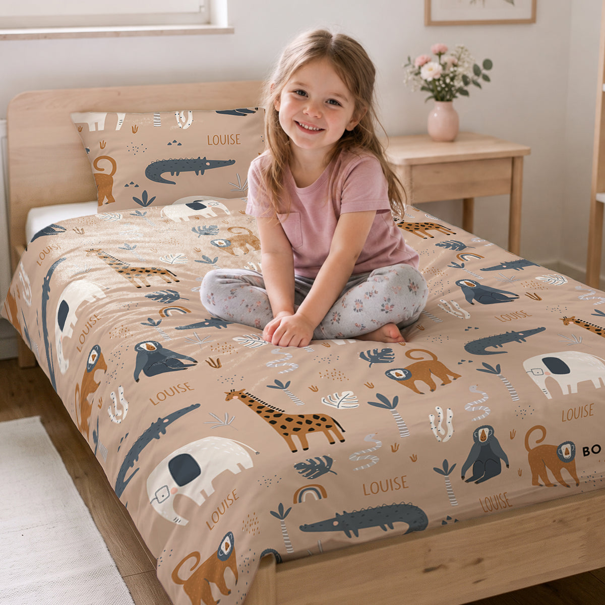 Fillette souriante assise sur son lit avec la parure Savane et le prénom market_france