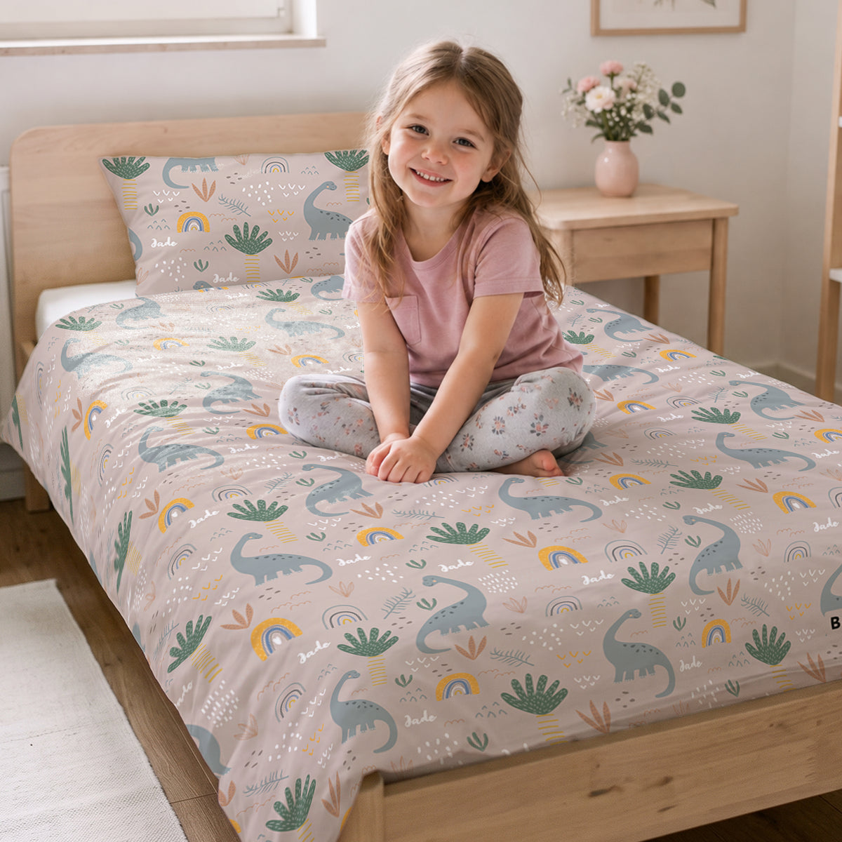 Petite fille souriante assise sur le lit avec la parure Dinosaures market_france